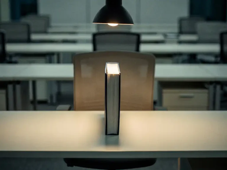 Dikke contractmap op een leeg facilitair bureau, verlicht door een bureaulamp in een stille, moderne kantooromgeving.